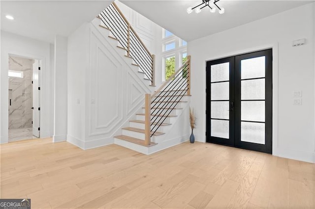 foyer with french doors, a notable chandelier, and light hardwood / wood-style flooring