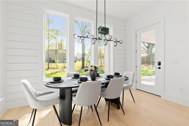 dining space with light hardwood / wood-style flooring and a notable chandelier