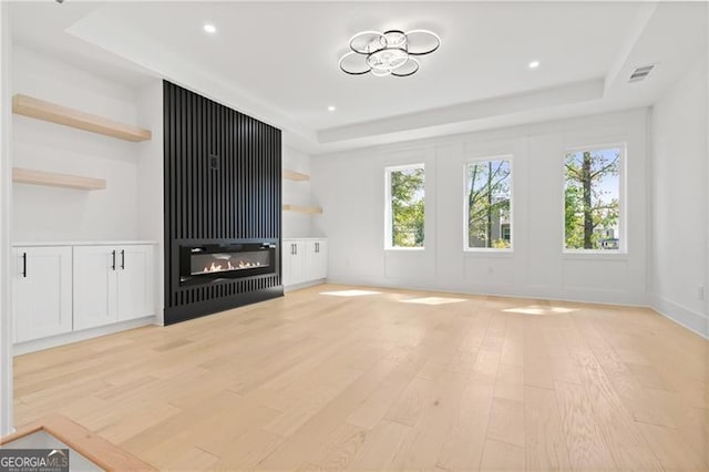 unfurnished living room with a large fireplace, a raised ceiling, and a wealth of natural light