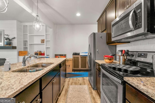 kitchen featuring sink, light stone counters, dark brown cabinets, appliances with stainless steel finishes, and light wood-type flooring