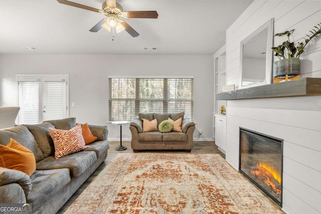 living room with built in shelves, ceiling fan, plenty of natural light, and light hardwood / wood-style flooring