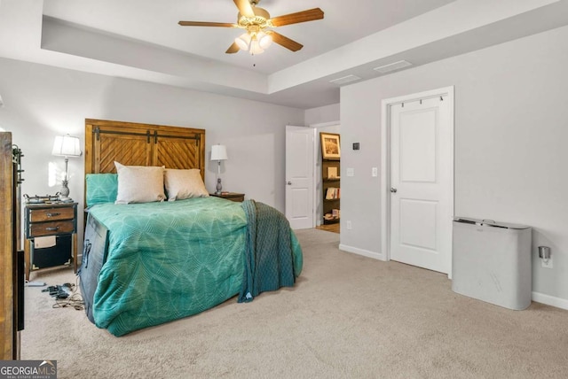 carpeted bedroom featuring a raised ceiling and ceiling fan