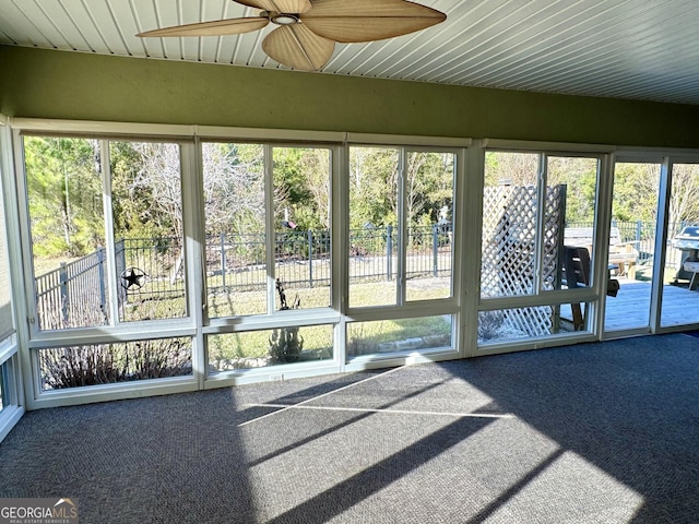 unfurnished sunroom featuring ceiling fan and a healthy amount of sunlight