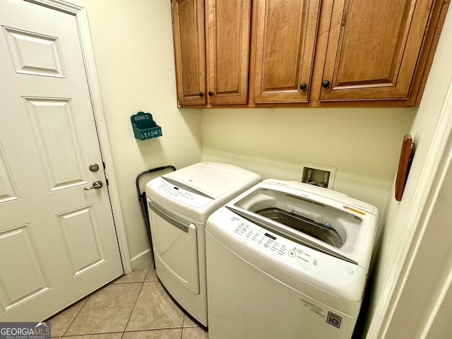 laundry area featuring washer and dryer, cabinets, and light tile patterned flooring