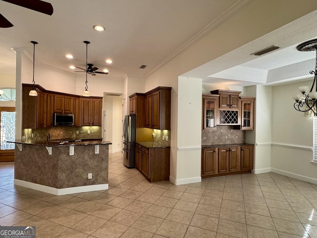 kitchen with appliances with stainless steel finishes, decorative light fixtures, light tile patterned floors, ceiling fan with notable chandelier, and ornamental molding