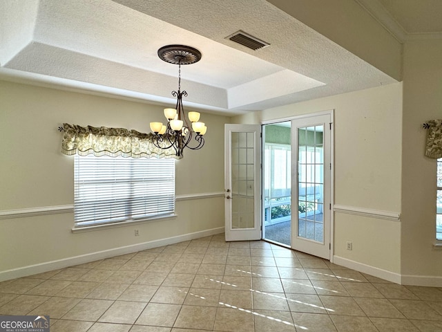 interior space featuring french doors, a textured ceiling, a tray ceiling, an inviting chandelier, and tile patterned flooring