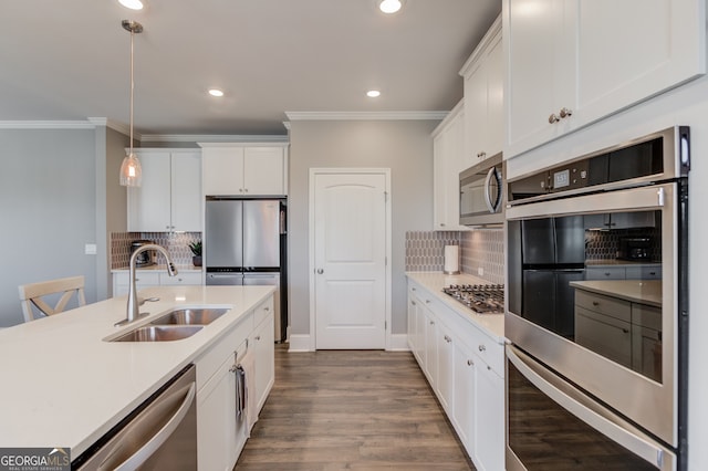 kitchen with pendant lighting, sink, decorative backsplash, white cabinetry, and stainless steel appliances