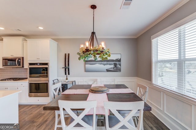 dining space featuring dark wood-type flooring, crown molding, and a chandelier