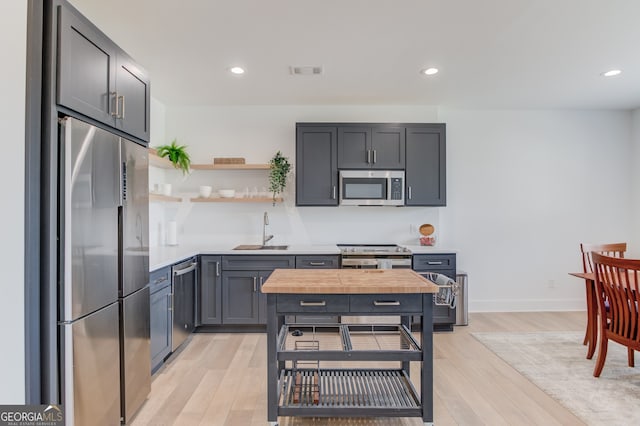 kitchen with gray cabinets, sink, light wood-type flooring, and appliances with stainless steel finishes