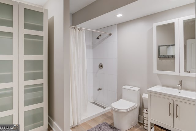 bathroom featuring wood-type flooring, vanity, toilet, and curtained shower