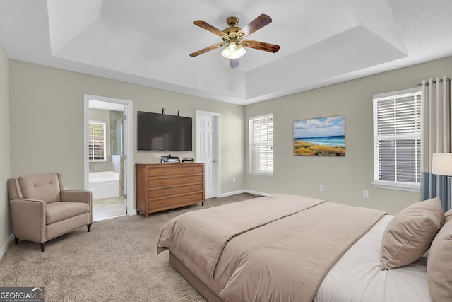 carpeted bedroom featuring ceiling fan, connected bathroom, and a tray ceiling