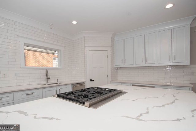 kitchen featuring decorative backsplash, light stone counters, sink, and gas cooktop