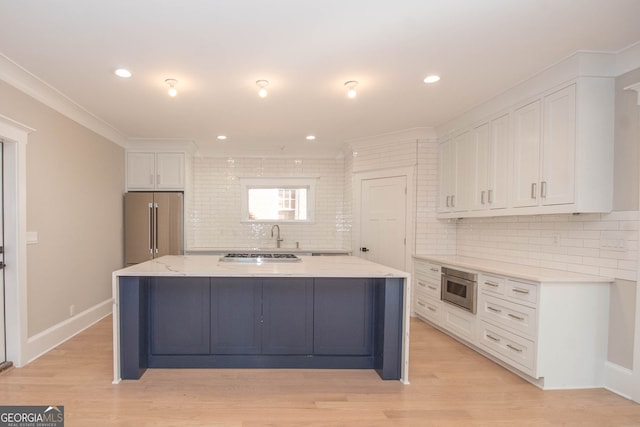 kitchen with tasteful backsplash, high end refrigerator, white cabinetry, and a center island