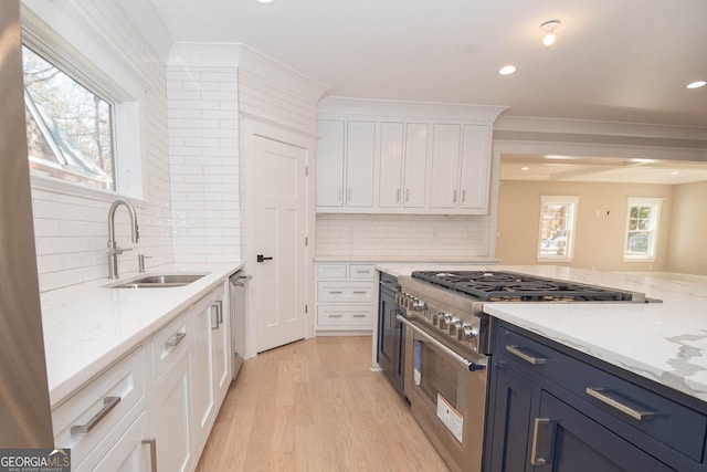 kitchen featuring sink, tasteful backsplash, light stone counters, white cabinets, and appliances with stainless steel finishes