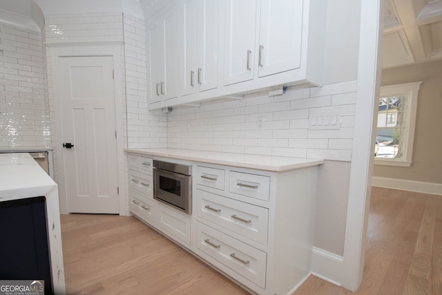 kitchen with tasteful backsplash, white cabinets, and light hardwood / wood-style floors