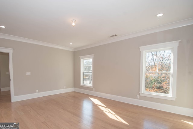 empty room with light hardwood / wood-style flooring, a wealth of natural light, and ornamental molding