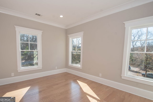 unfurnished room with light wood-type flooring, crown molding, and a healthy amount of sunlight