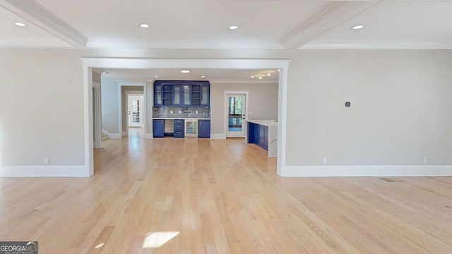 unfurnished living room featuring beamed ceiling, light wood-type flooring, and ornamental molding