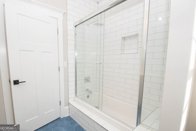 bathroom featuring tile patterned flooring and shower / bath combination with glass door