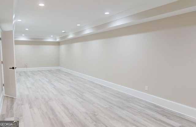 basement with ornamental molding and light hardwood / wood-style flooring