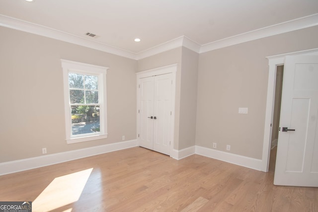 unfurnished bedroom with crown molding, a closet, and light hardwood / wood-style floors