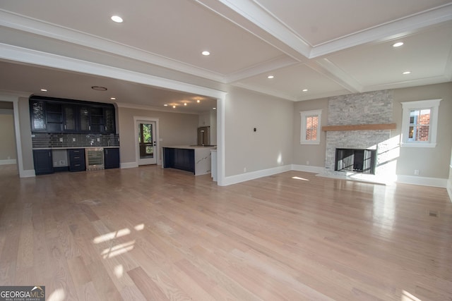 unfurnished living room with beamed ceiling, crown molding, a fireplace, and hardwood / wood-style flooring