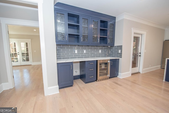 kitchen featuring french doors, tasteful backsplash, wine cooler, blue cabinets, and light hardwood / wood-style floors