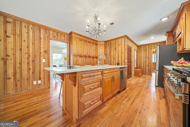 kitchen featuring stainless steel appliances, a notable chandelier, decorative light fixtures, a kitchen island with sink, and a breakfast bar