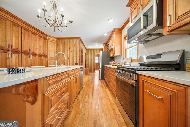 kitchen featuring sink, stainless steel appliances, a notable chandelier, light hardwood / wood-style floors, and pendant lighting