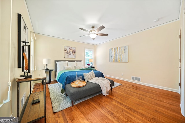 bedroom with ceiling fan, wood-type flooring, and ornamental molding