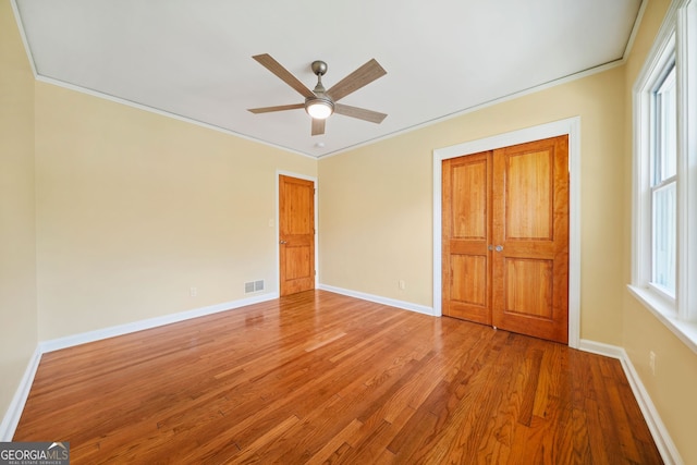 unfurnished bedroom with ceiling fan, hardwood / wood-style floors, and ornamental molding