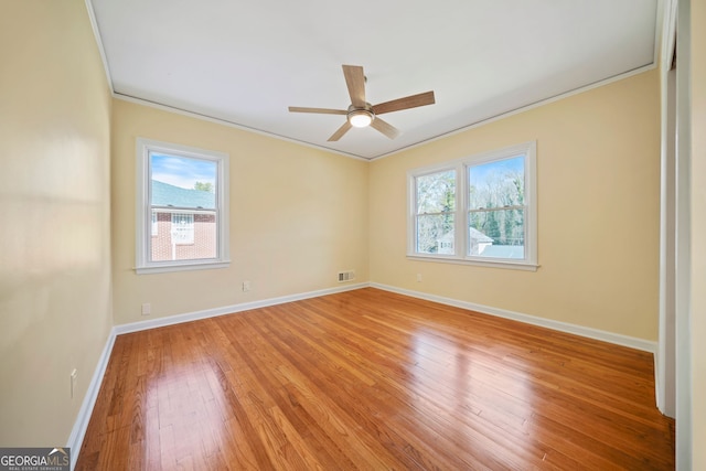 empty room featuring ceiling fan, hardwood / wood-style floors, plenty of natural light, and ornamental molding