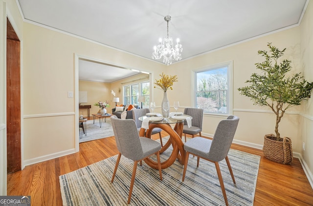 dining area featuring hardwood / wood-style flooring, ornamental molding, and a chandelier