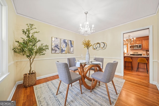 dining space with ornamental molding, a notable chandelier, and light wood-type flooring