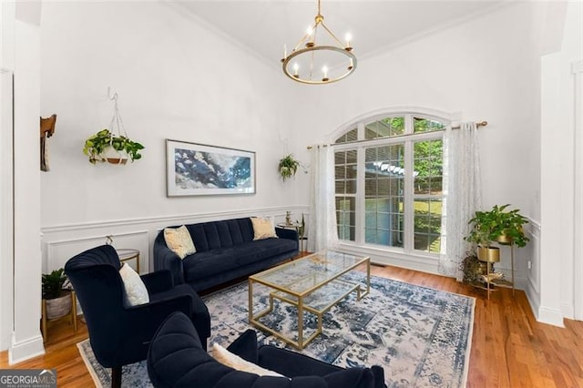 living room featuring wood-type flooring, ornamental molding, and a notable chandelier