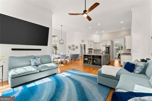 living room with light wood-type flooring, ceiling fan, and sink