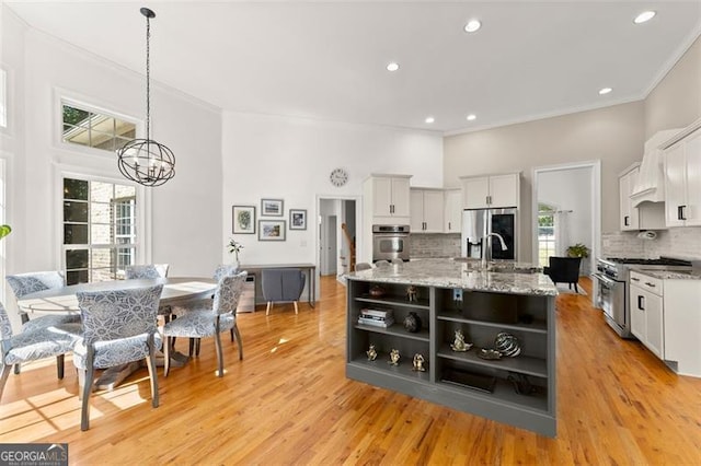 kitchen featuring backsplash, stainless steel appliances, white cabinetry, and hanging light fixtures