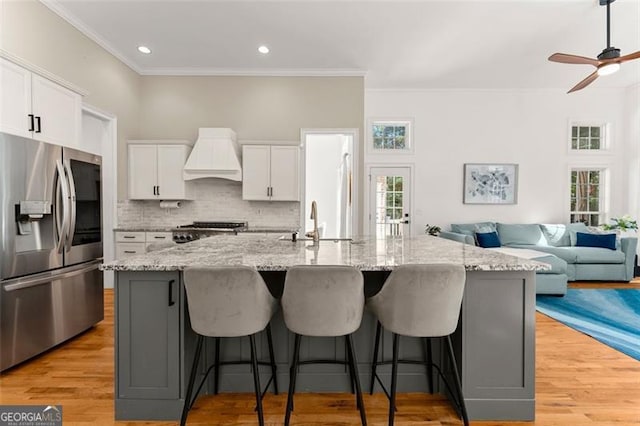kitchen with stove, custom exhaust hood, a sink, stainless steel fridge with ice dispenser, and crown molding