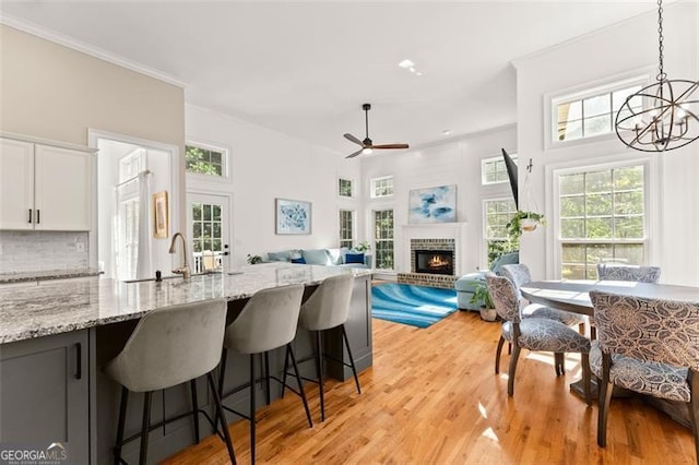 kitchen featuring white cabinetry, light stone countertops, sink, hanging light fixtures, and a fireplace