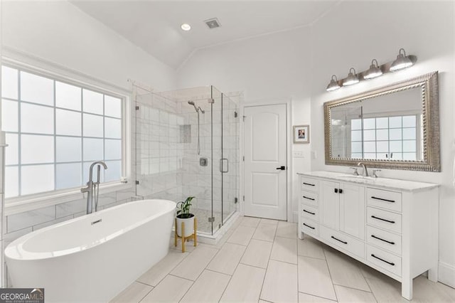 full bathroom featuring a shower stall, lofted ceiling, vanity, and a freestanding tub