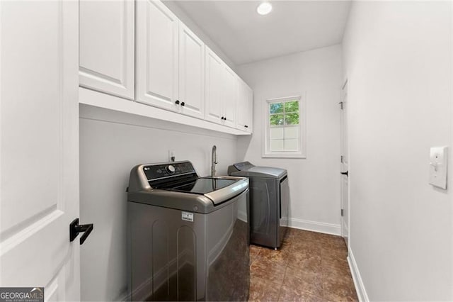 clothes washing area with washer and clothes dryer and cabinets