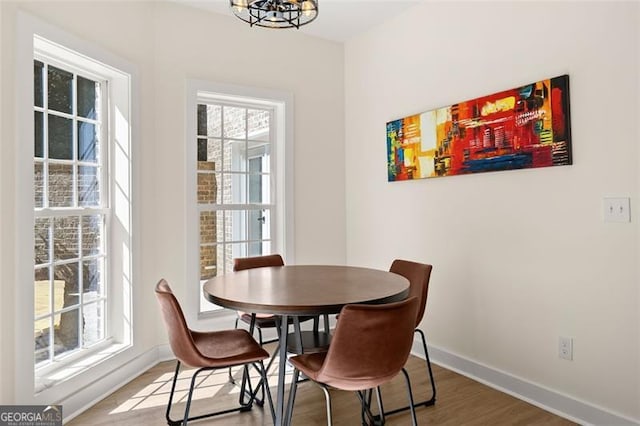 dining room with hardwood / wood-style floors, an inviting chandelier, and plenty of natural light