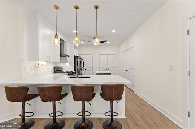 kitchen with white cabinets, hanging light fixtures, a kitchen bar, kitchen peninsula, and stainless steel appliances