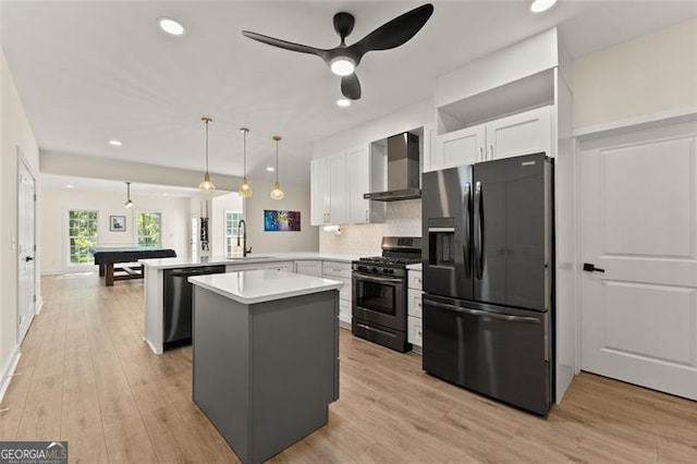 kitchen with a sink, wall chimney range hood, black fridge with ice dispenser, dishwashing machine, and stainless steel gas range