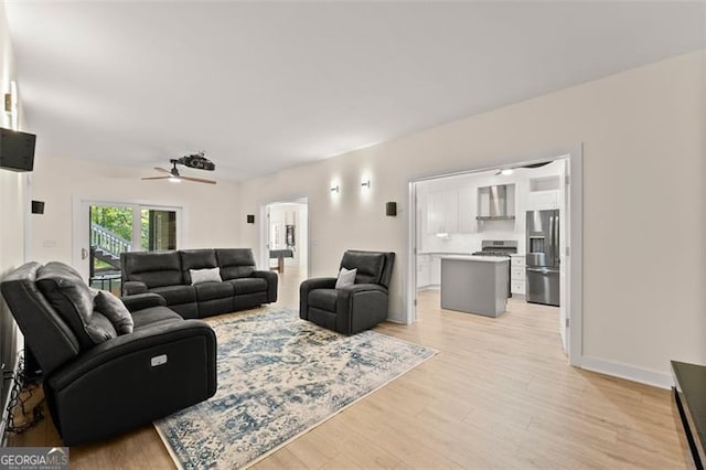 living area featuring light wood-style flooring and a ceiling fan