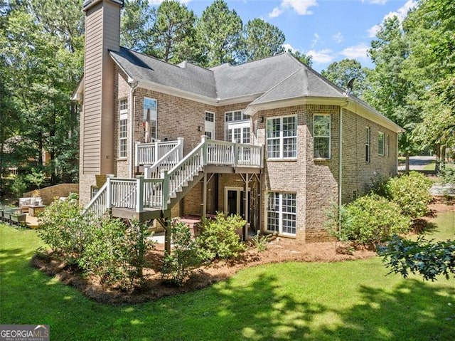 back of property with brick siding, stairway, a deck, and a lawn