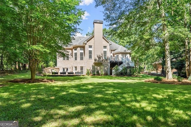back of property with a chimney, a yard, stairway, and a wooden deck