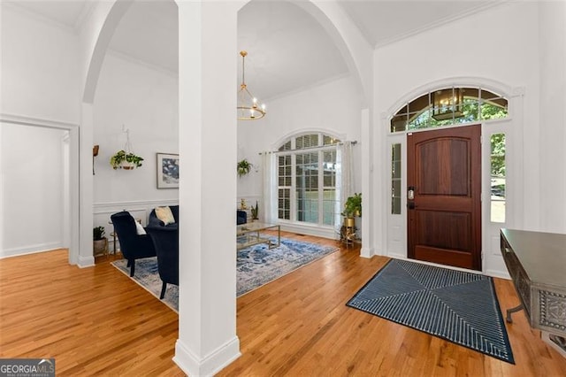 entrance foyer with a high ceiling, light wood-type flooring, and an inviting chandelier