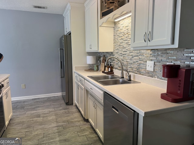 kitchen with light hardwood / wood-style floors, stainless steel appliances, a textured ceiling, sink, and white cabinetry