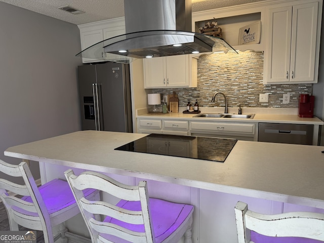 kitchen featuring stainless steel appliances, island exhaust hood, a breakfast bar, tasteful backsplash, and sink